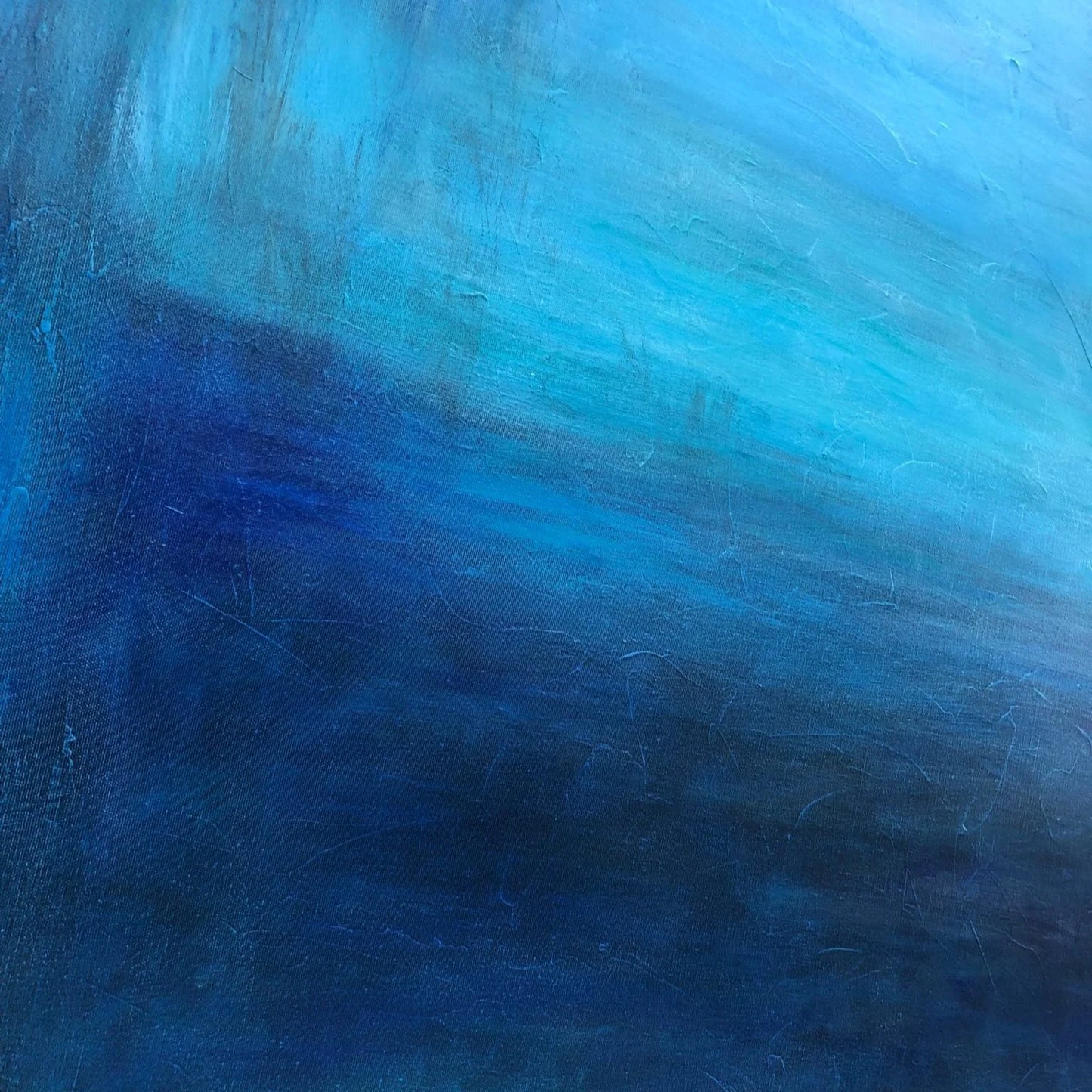 The image is a close-up of a textured blue surface, possibly a painting or a wall. The color palette is dominated by shades of blue, ranging from a darker shade to a lighter one, creating a sense of depth and dimension. The surface appears to be slightly worn, with visible scratches and marks, adding a sense of age and character to the image.