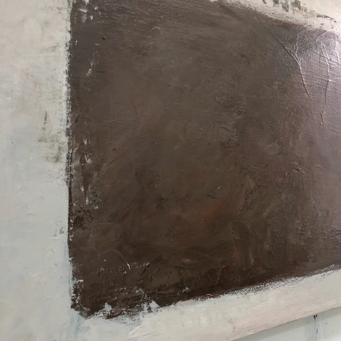 The image is a close-up of a dark brown, textured surface, possibly a painting or a wall.