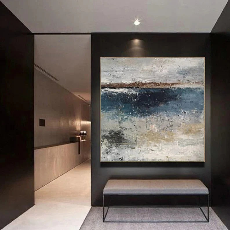 a modern art piece hanging on a wall in a hallway. The painting depicts a landscape with a blue sky and water, creating a serene and calming atmosphere. The hallway is well-lit, with a bench placed in front of the painting, providing a comfortable seating area for visitors to appreciate the artwork.