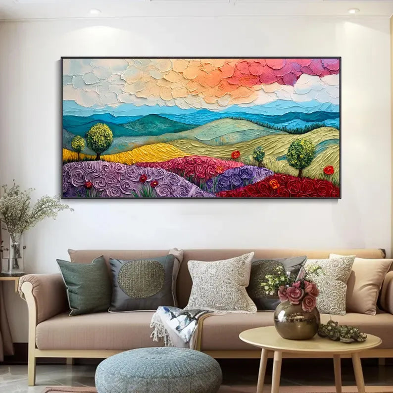 a large, colorful painting of a landscape with mountains, flowers, and trees hanging on a wall above a couch in a living room setting.