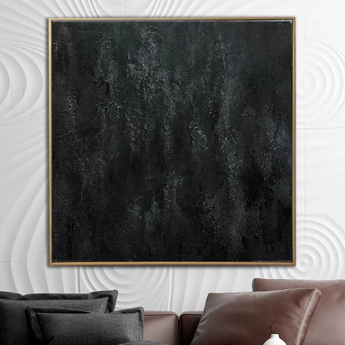 a large, square black painting hanging on a white wall above a brown leather couch.