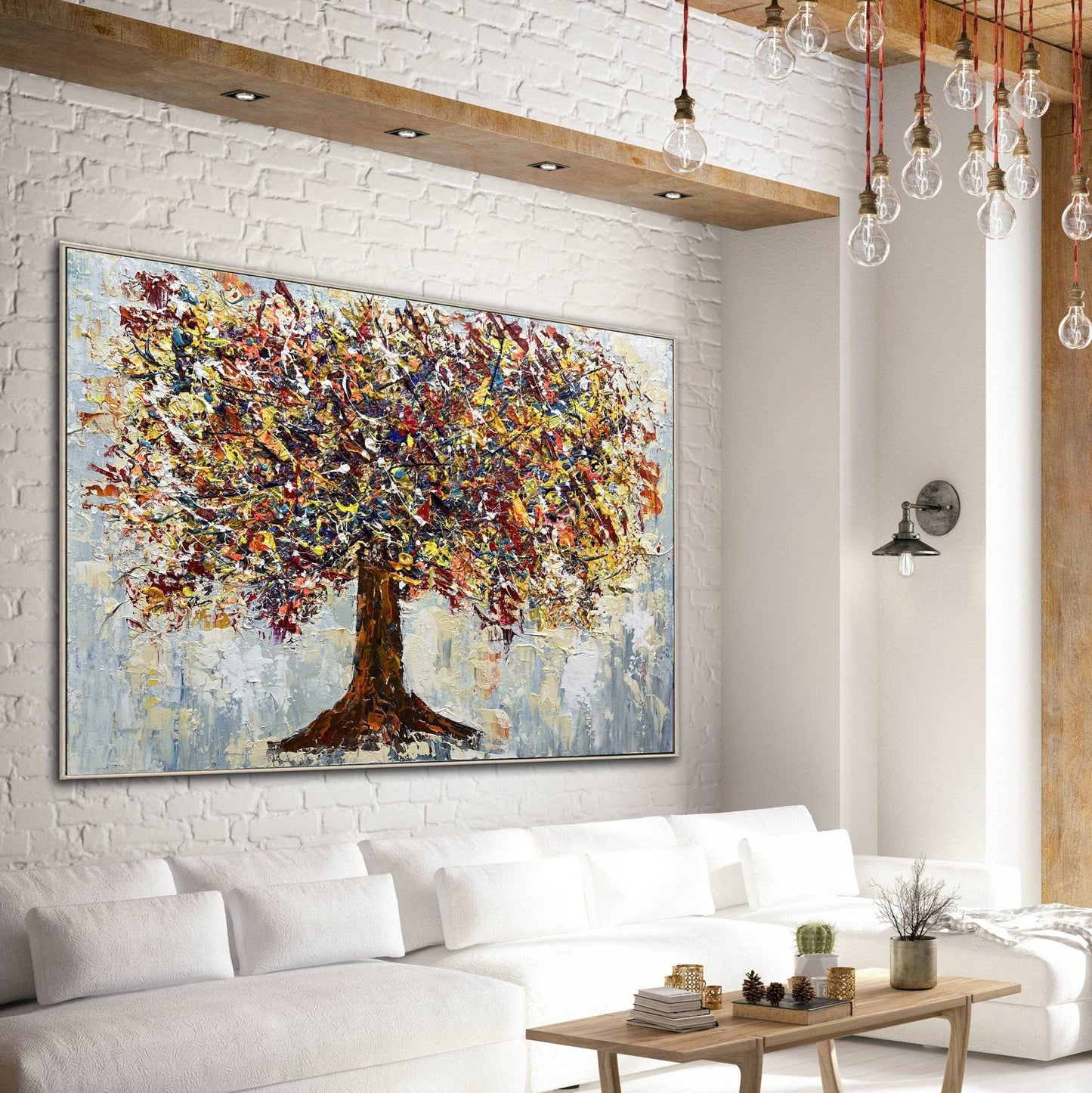 a large, colorful painting of a tree hanging on a white brick wall in a modern living room setting.