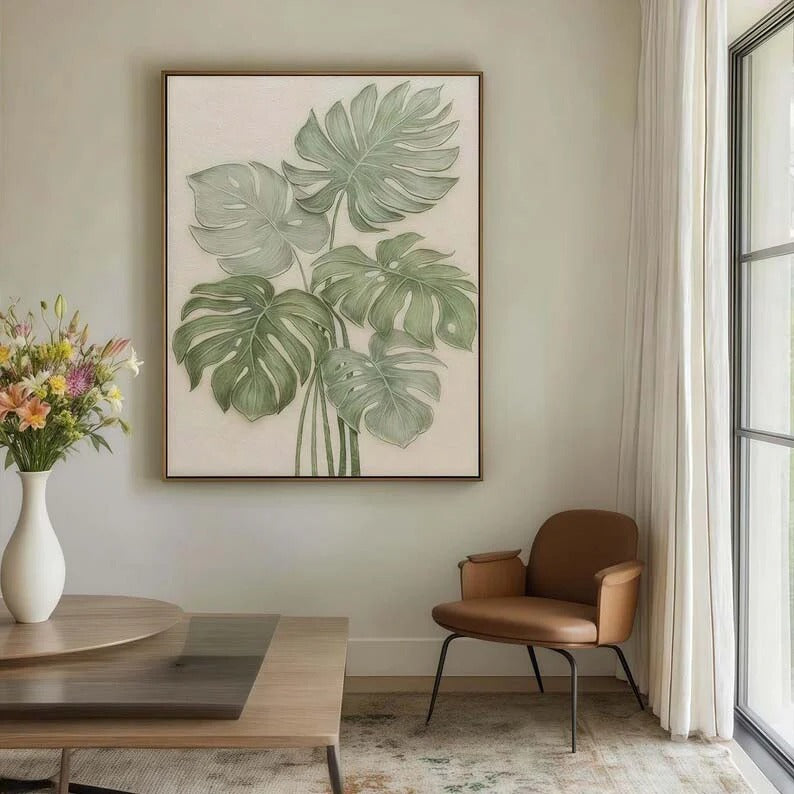 a living room with a large framed painting of green leaves hanging on the wall, a wooden coffee table in front of the painting, and a brown leather armchair to the side.