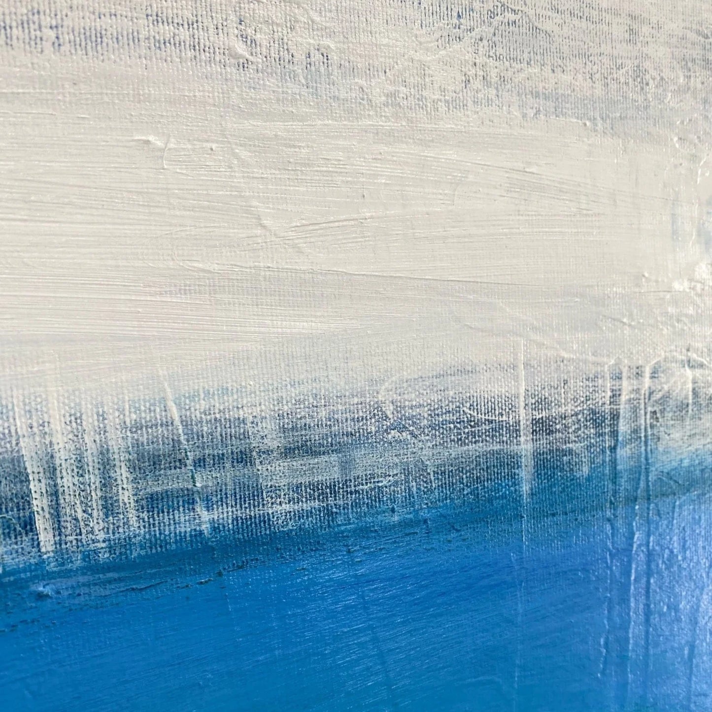 The image is a close-up of a textured surface with a gradient of blue and white colors. The surface appears to be a painting or artwork, with a textured and layered appearance.