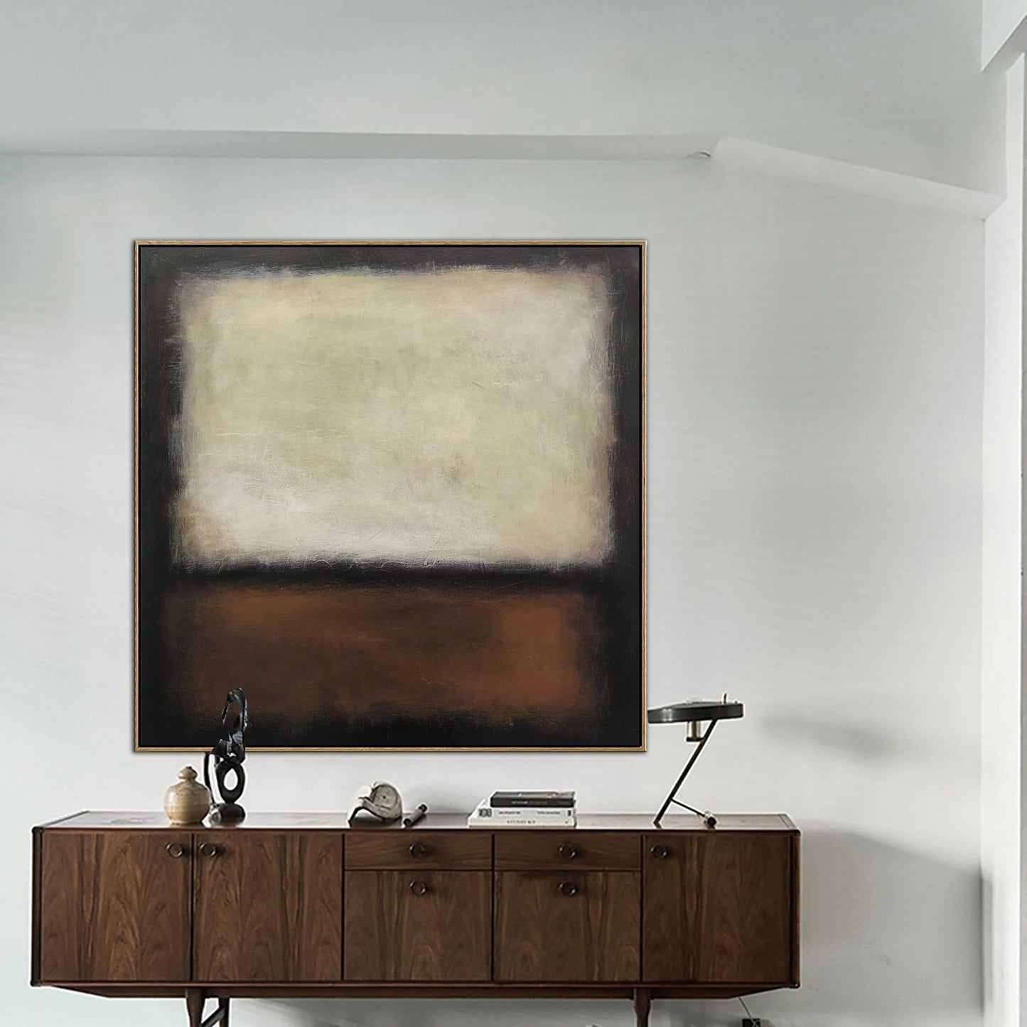 a large abstract painting hanging on a white wall above a wooden cabinet with drawers. The cabinet has a small sculpture and a lamp on top of it.