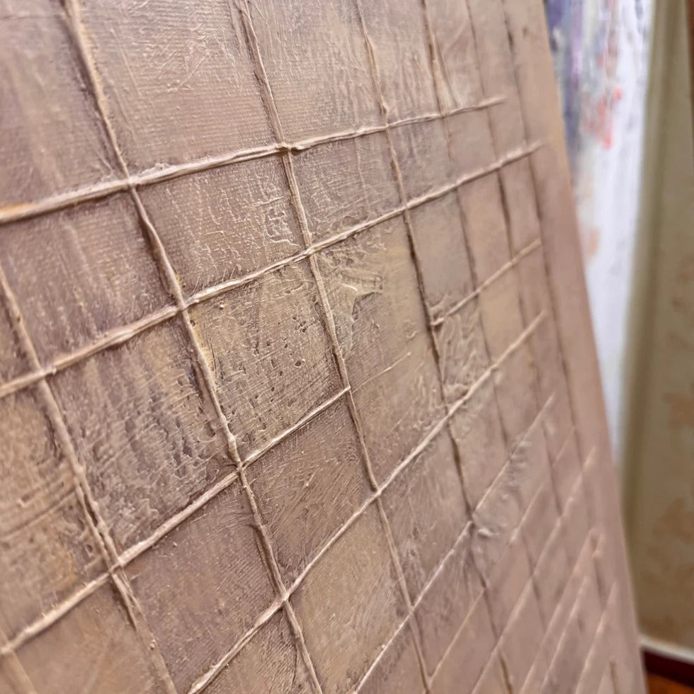 a close-up view of a textured surface, possibly a wooden panel or a canvas, with a grid-like pattern. The surface appears to be made of a material that resembles wood or a similar natural texture.