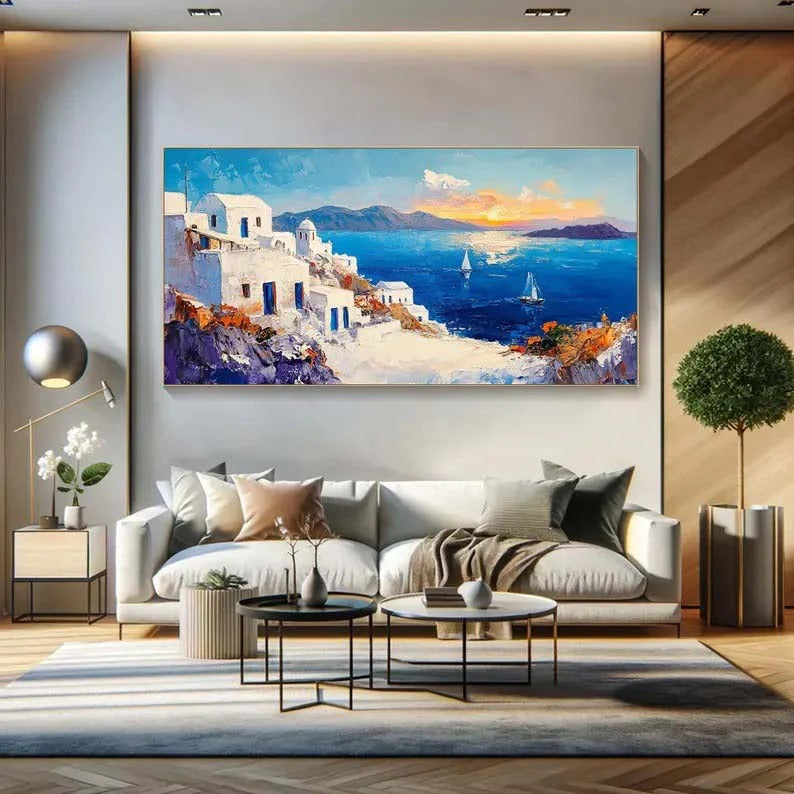 a large, colorful painting of a coastal town with white buildings, blue sky, and boats on the water. The painting is displayed on a wall above a white sofa in a modern living room setting.