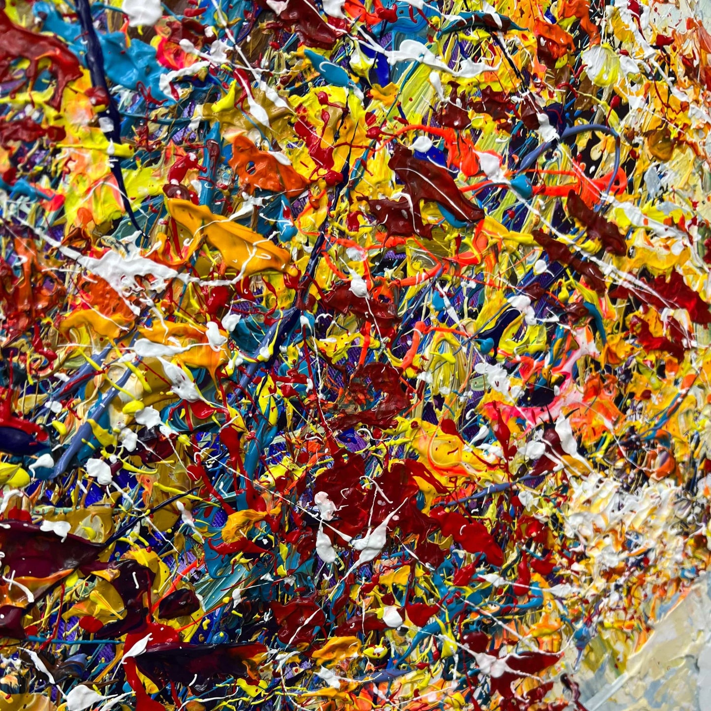 The image is a vibrant and colorful abstract painting, featuring a variety of bold and bright colors such as red, yellow, blue, and orange. The painting appears to be a dynamic and energetic composition, with splashes of paint covering the canvas in a seemingly random and spontaneous manner.