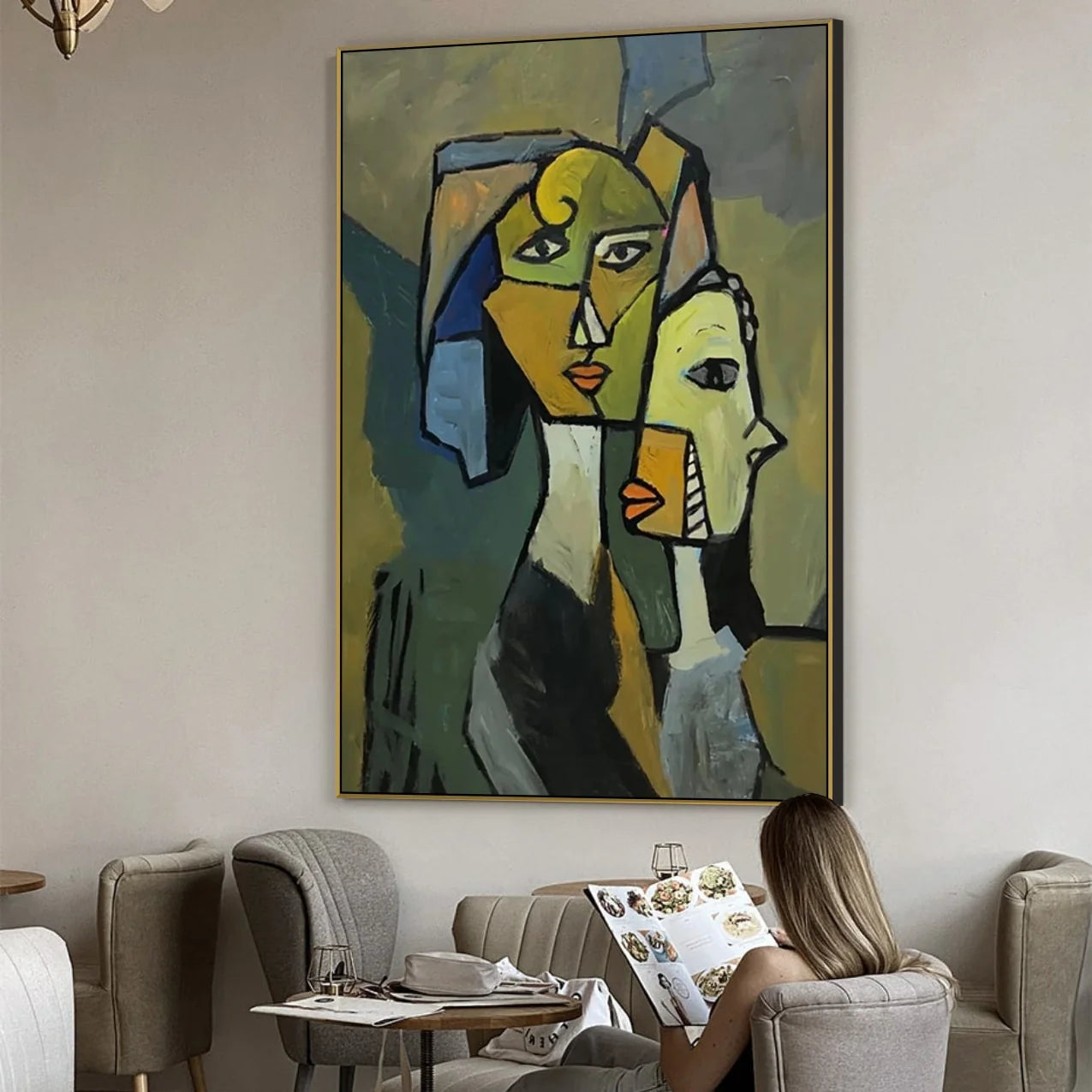 a large abstract painting hanging on a wall, with a woman sitting in a chair and reading a book in front of it.