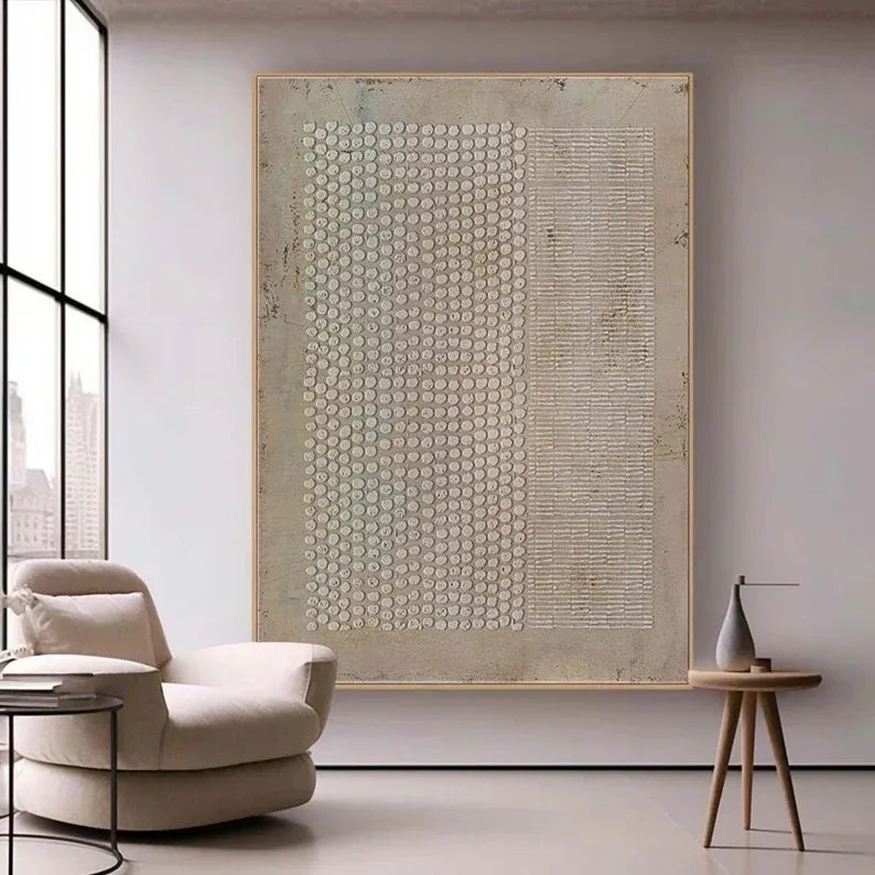 a modern living room with a large abstract painting on the wall, a beige armchair, and a small wooden side table with a vase.