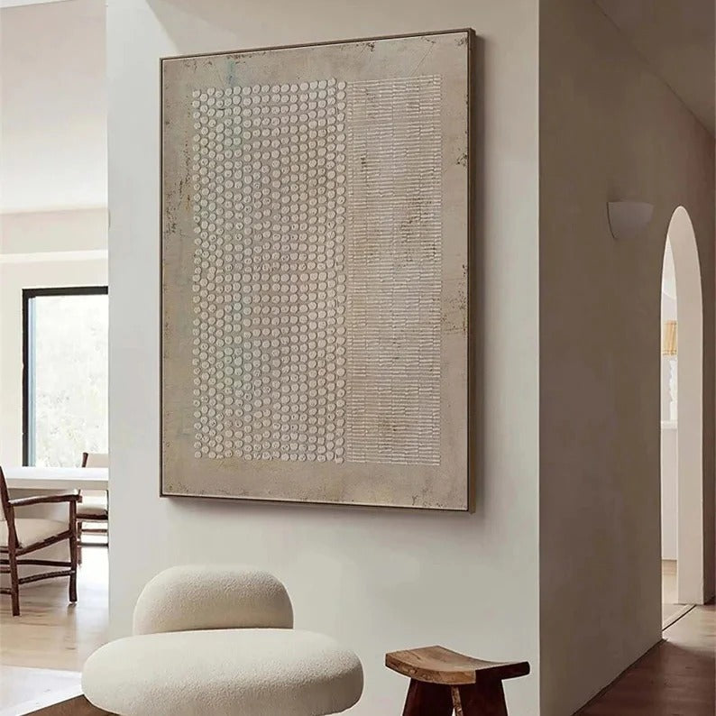 a minimalist living room with a large abstract painting on the wall, a wooden stool, and a dining table in the background.