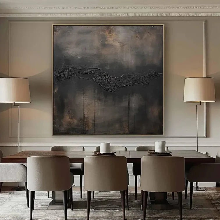 a modern dining room with a large abstract painting hanging on the wall above a wooden dining table. The table is set with three chairs, and there are two floor lamps on either side of the table. The overall color scheme of the room is neutral, with a dark gray and brown palette.