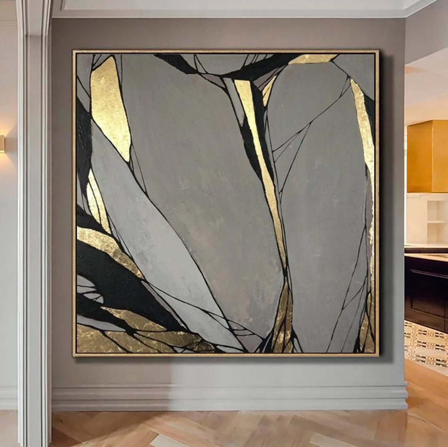 a large abstract painting with a mix of gray, black, and gold colors, displayed on a wall in a room.