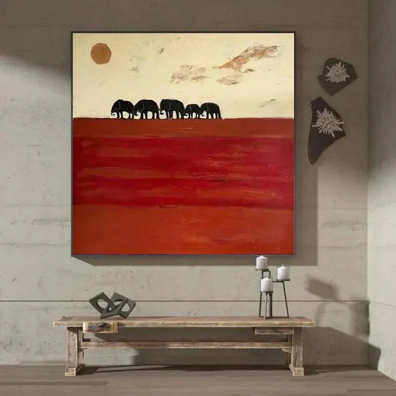 a large painting of elephants on a red background, hanging on a wall above a wooden bench.