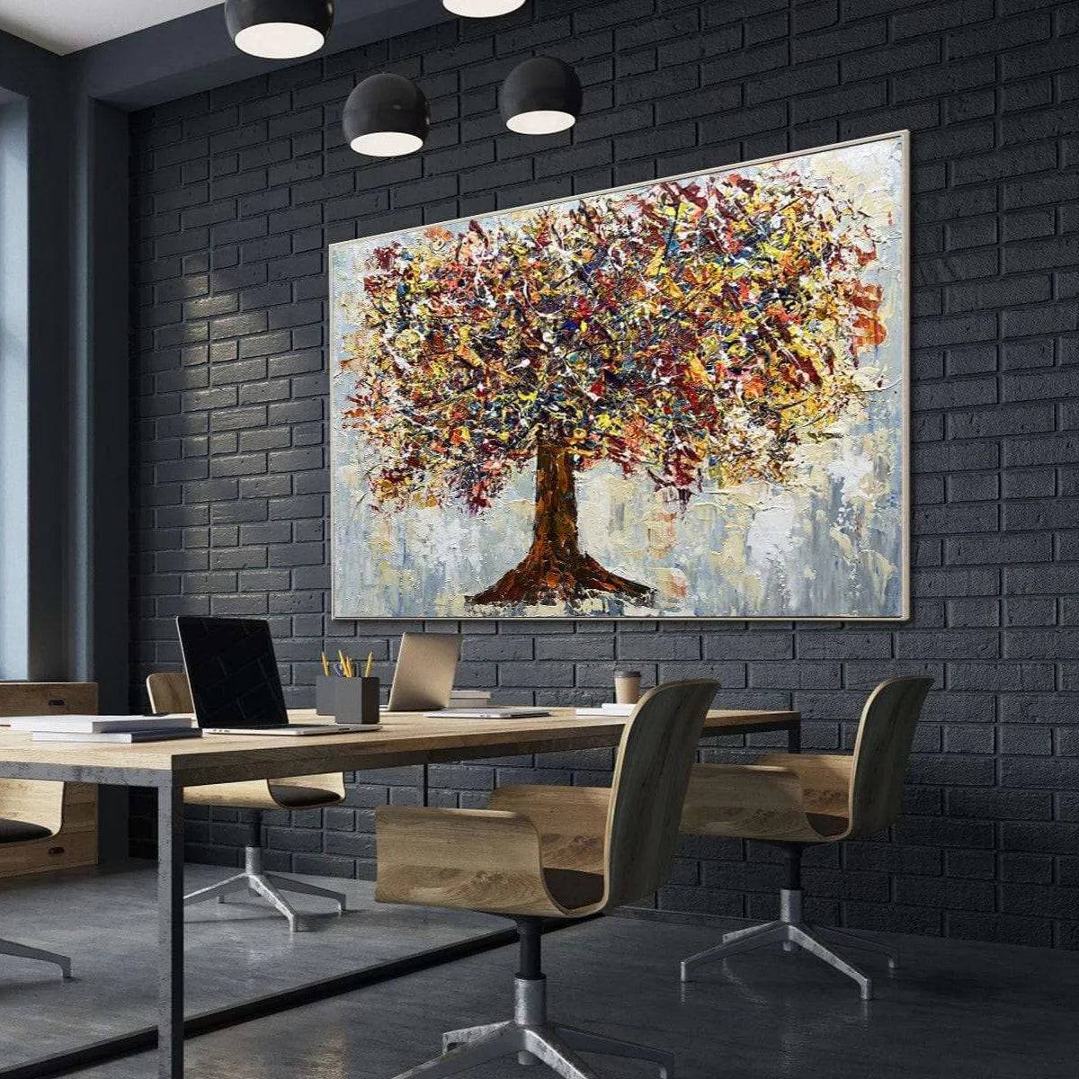 a modern office space with a large, colorful painting of a tree hanging on the wall. The painting is the focal point of the room, and it is surrounded by a wooden desk with a laptop, a coffee cup, and a chair. The office has a sleek, contemporary design with black brick walls and a gray floor.