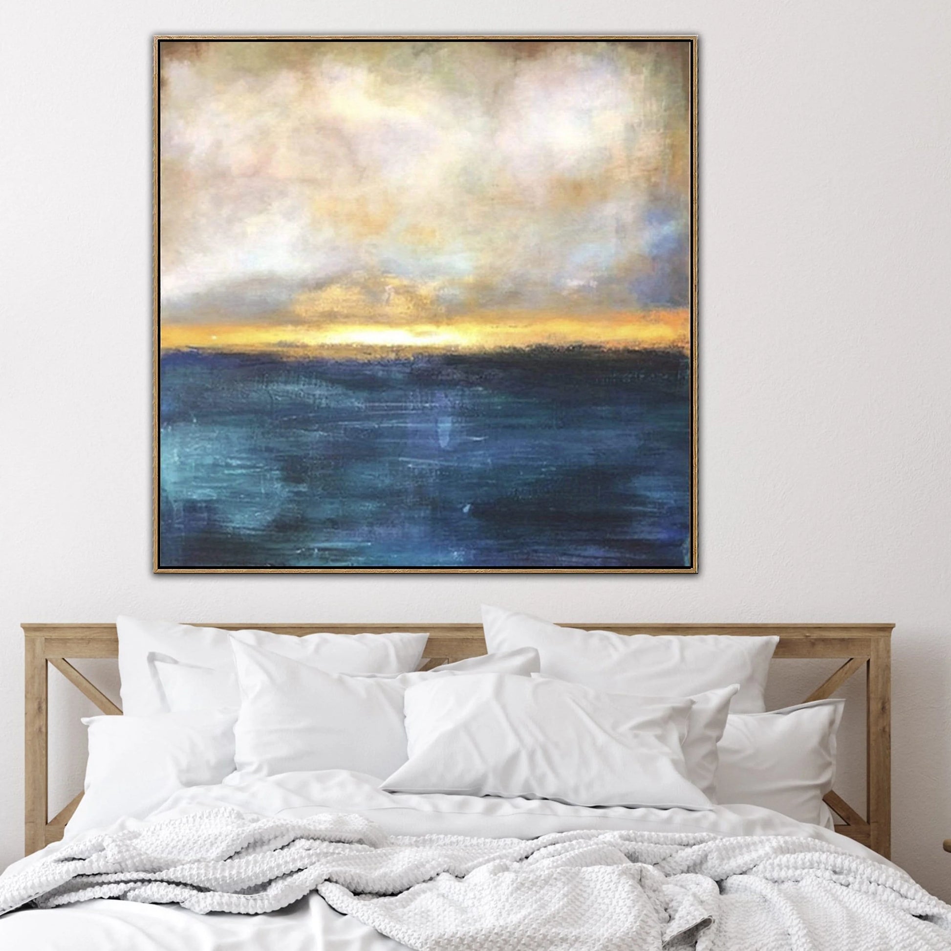 a large, vibrant painting of a seascape hanging above a bed with white pillows and a wooden headboard.