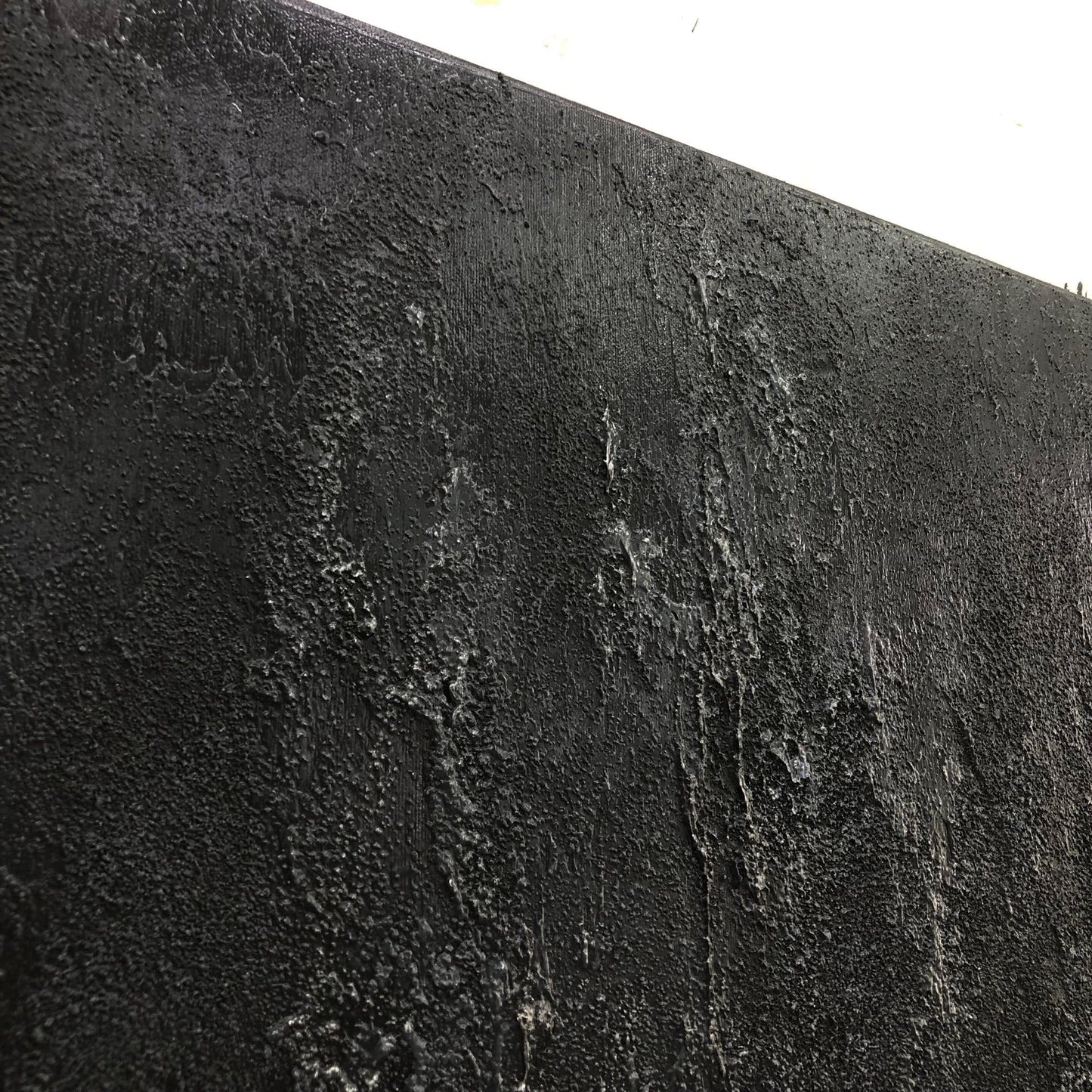 a close-up view of a textured, black surface with a rough, uneven appearance.