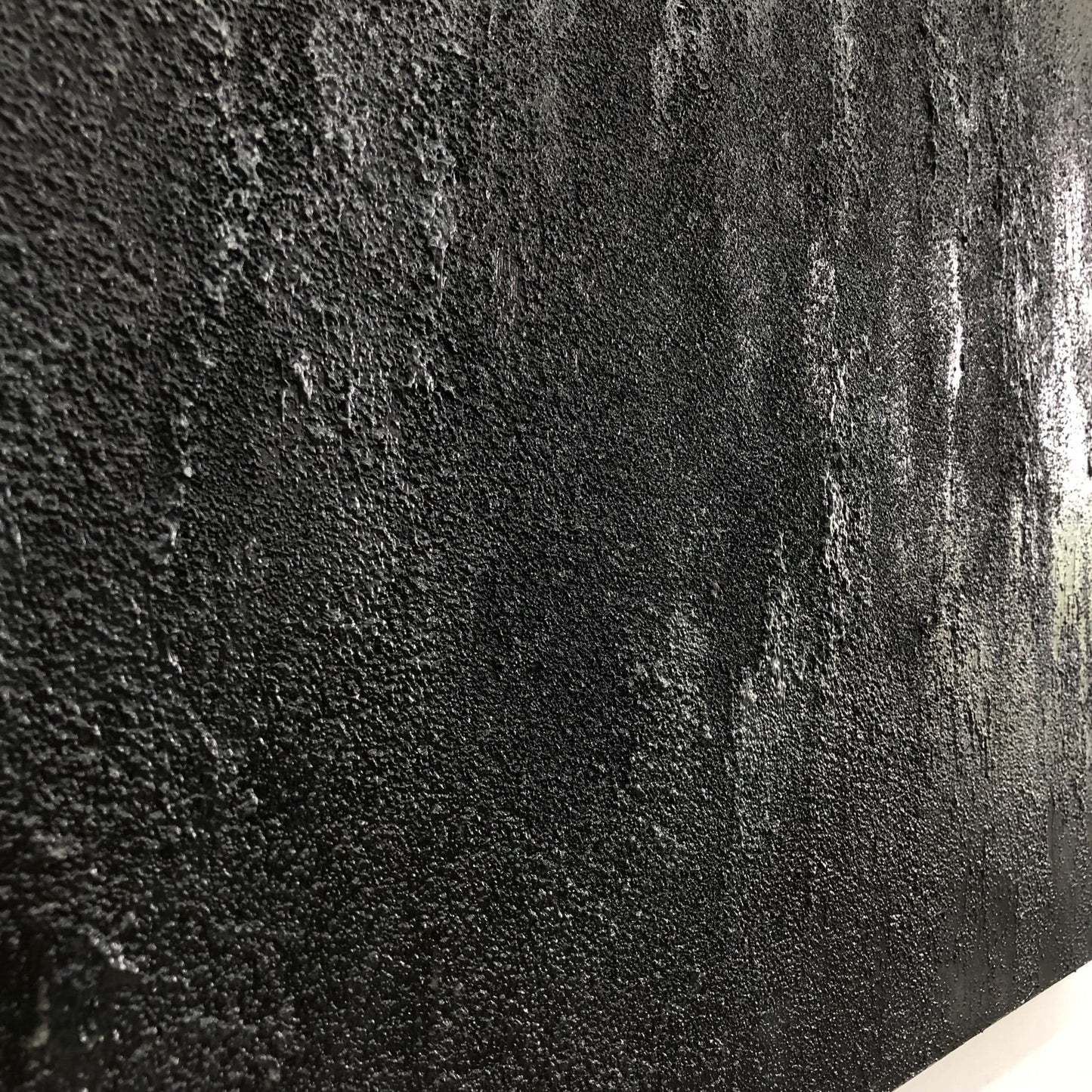 The image is a close-up of a textured surface, possibly a wall or a piece of fabric, with a dark, textured appearance.