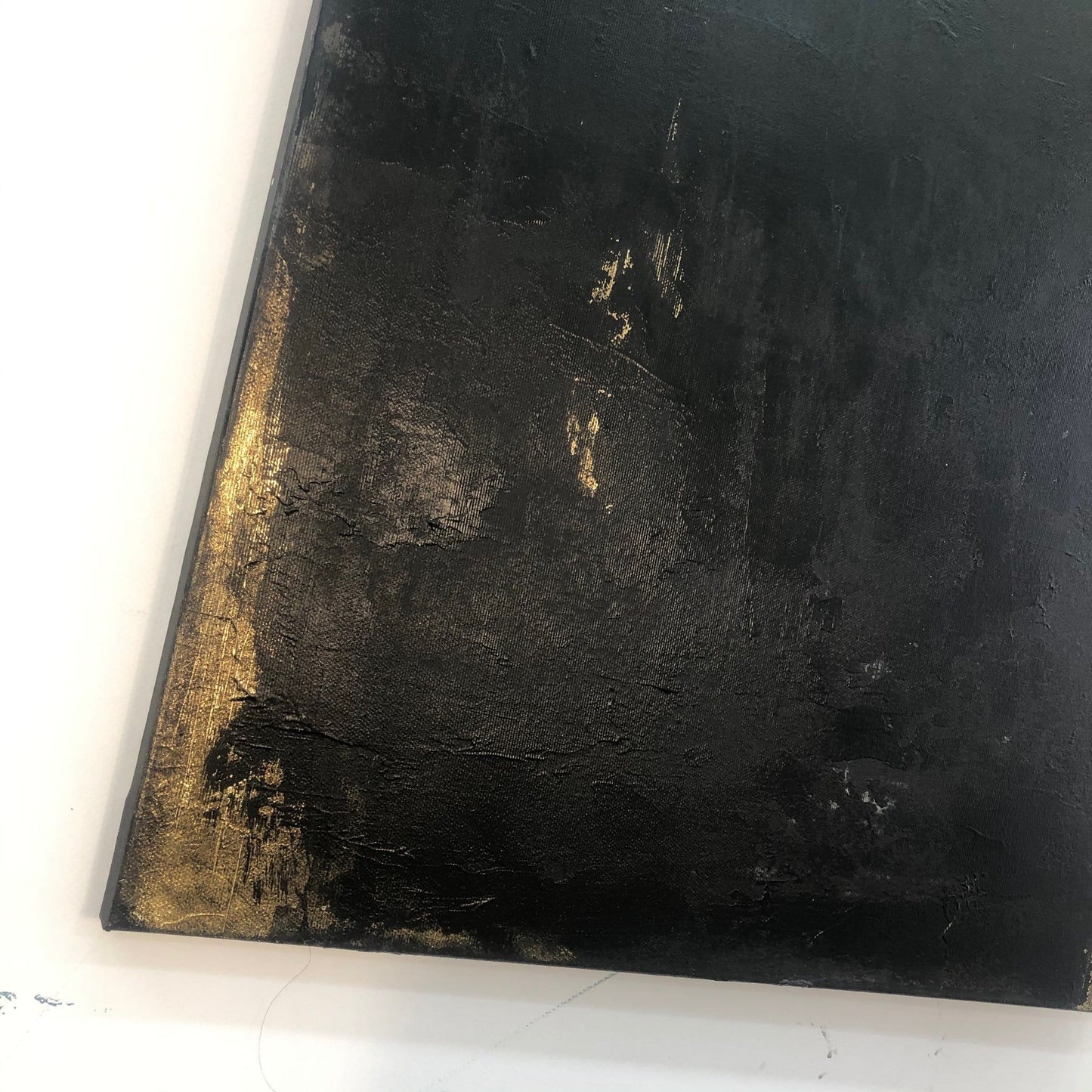 The image is a close-up of a black, textured surface with a gold or metallic texture, possibly a painting or artwork.