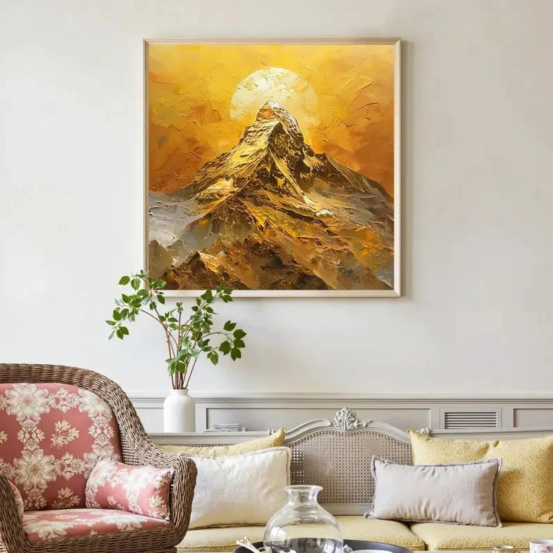 a large painting of a mountain landscape hanging on a wall, with a wicker chair and a coffee table in the foreground.