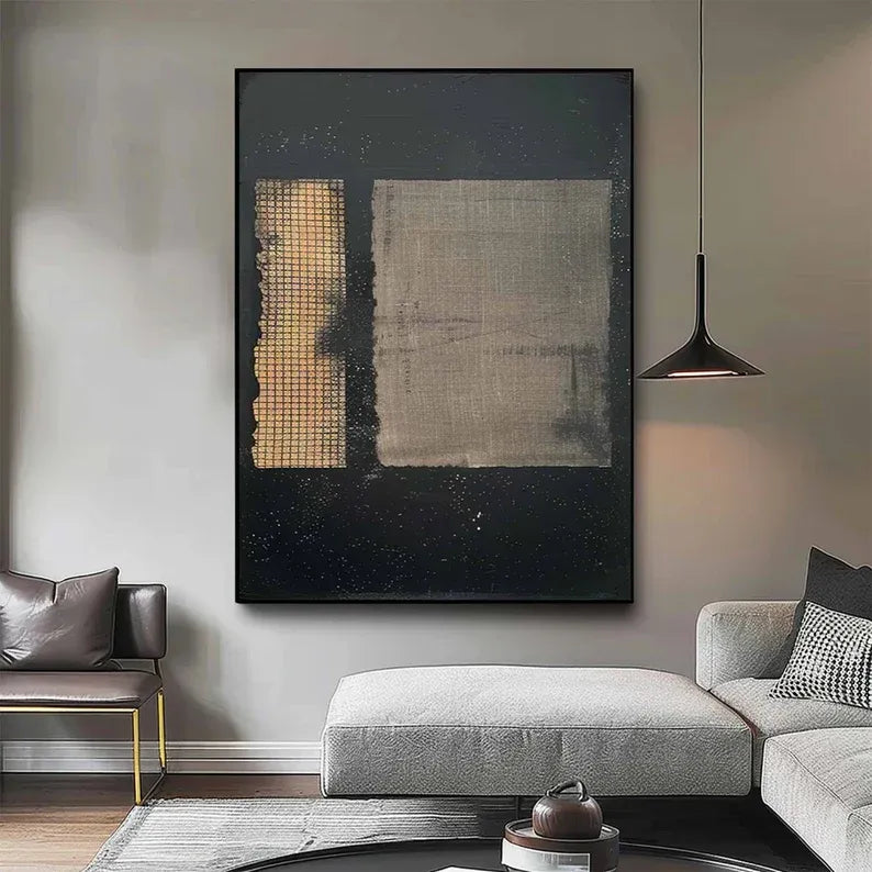 a modern living room with a large abstract painting hanging on the wall. The painting has a black background with a white square and a yellow rectangular shape on the left side. The room is furnished with a gray sofa, a coffee table, and a black pendant light.