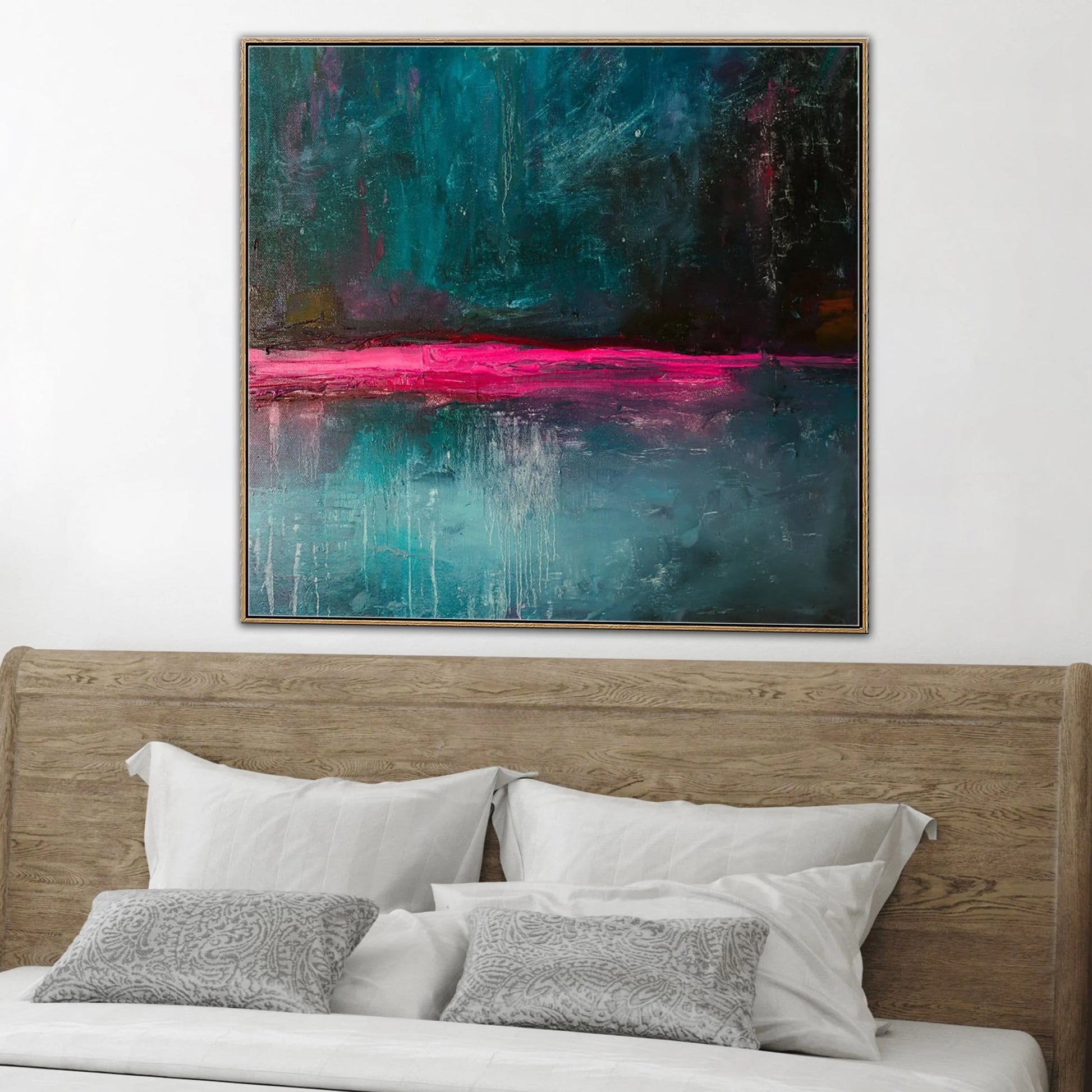 a large abstract painting hanging on a wall above a bed with white pillows and a wooden headboard.