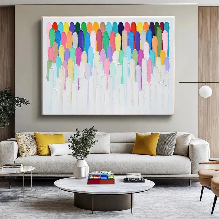 a modern living room with a large abstract painting hanging on the wall above a gray sofa. The sofa is adorned with yellow and gray throw pillows, and there is a round coffee table in front of it. The room also includes a potted plant, a vase, and a bookshelf, creating a cozy and stylish atmosphere.