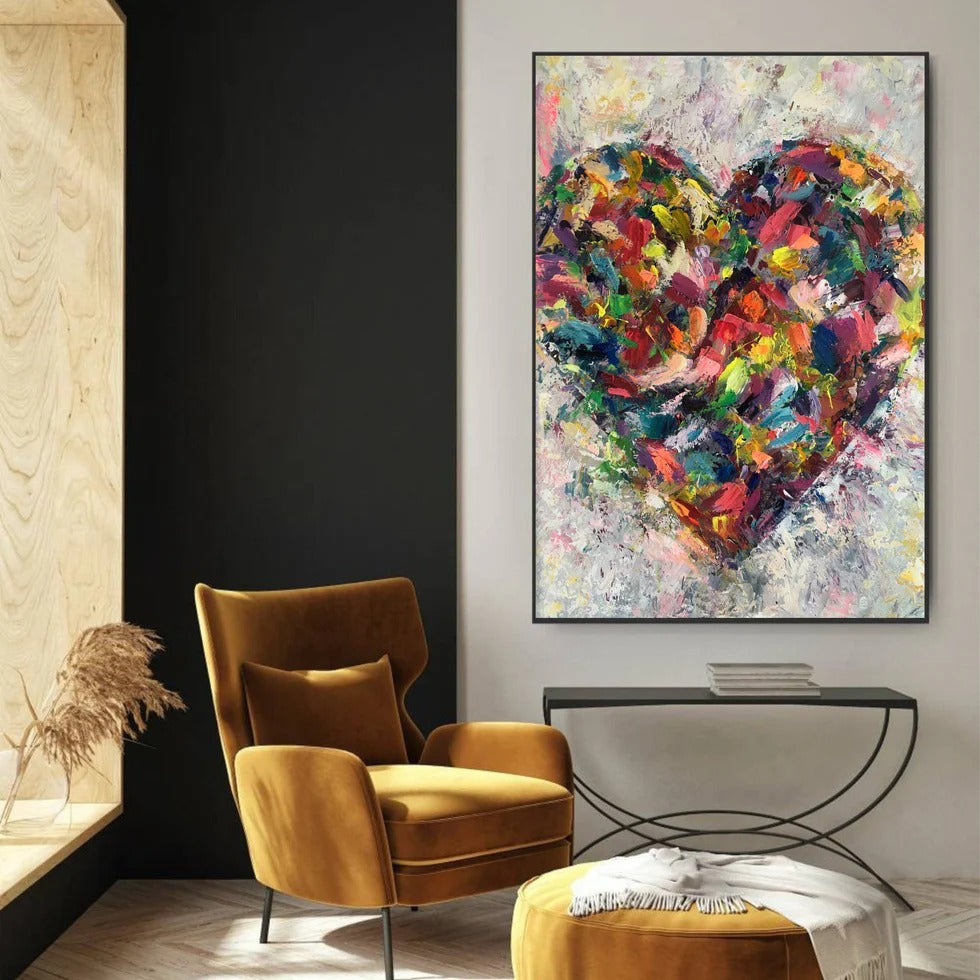 a modern living room with a large, colorful abstract painting of a heart as the focal point. The room is furnished with a yellow armchair and a black console table, creating a cozy and inviting atmosphere.