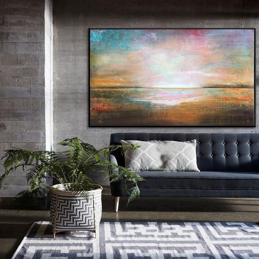 a living room with a large abstract painting hanging on the wall above a black sofa. The painting depicts a colorful landscape with a sunset and mountains in the background. The room also includes a potted plant and a geometric patterned rug, creating a cozy and inviting atmosphere.