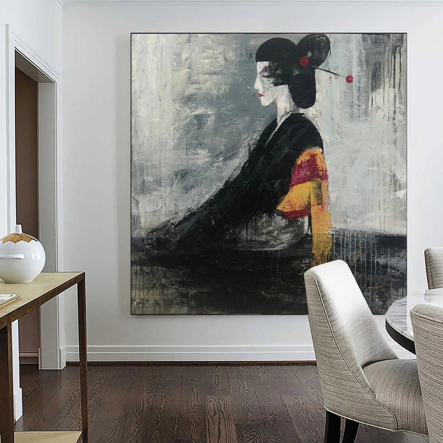 a large, abstract painting of a woman in a black and white style, with bold brushstrokes and a striking color palette. The painting is displayed on a wall in a room with a wooden floor and a dining table with chairs in the background.