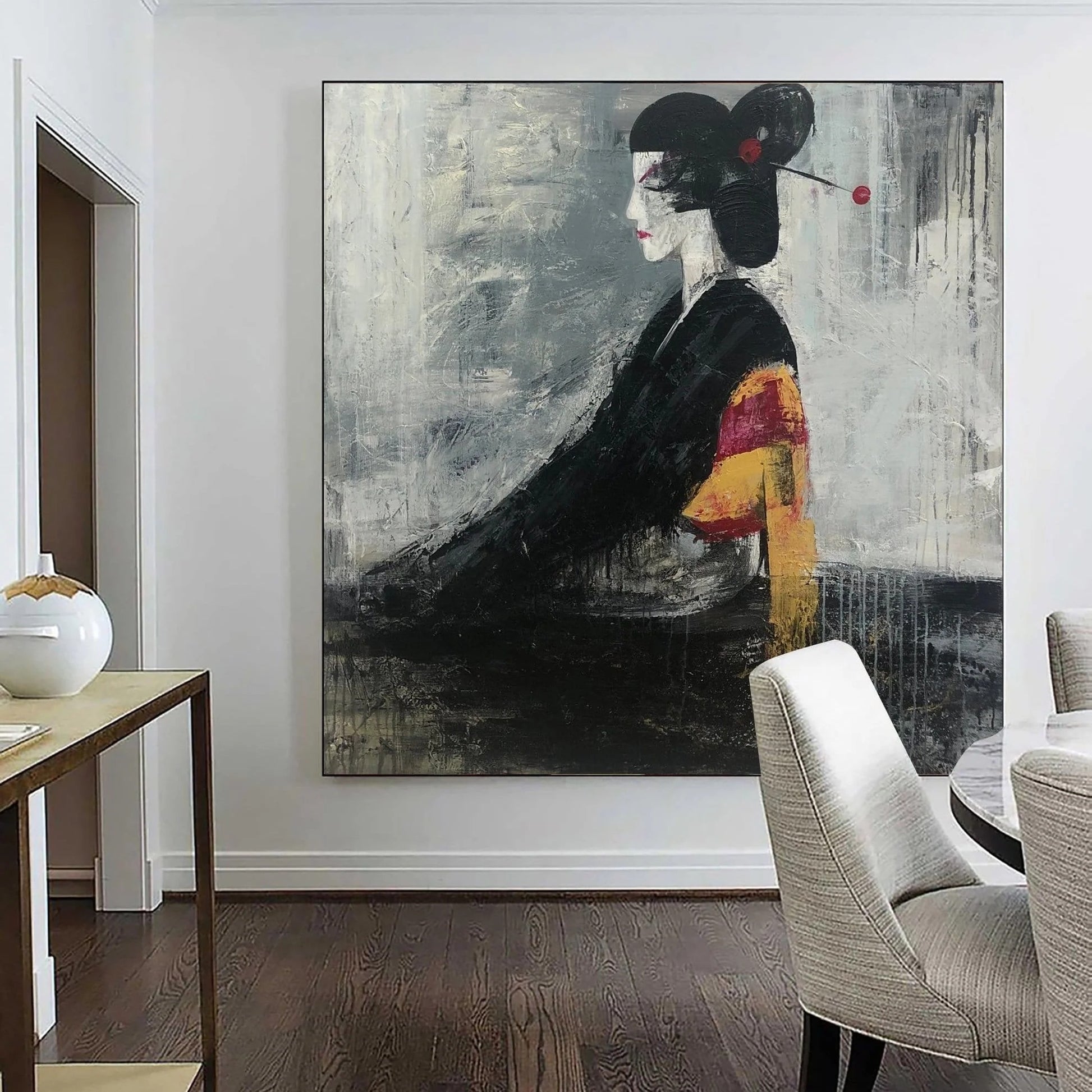 a large, abstract painting of a woman in a black and white style, with bold brushstrokes and a striking color palette. The painting is displayed on a wall in a room with a wooden floor and a dining table with chairs in the background.
