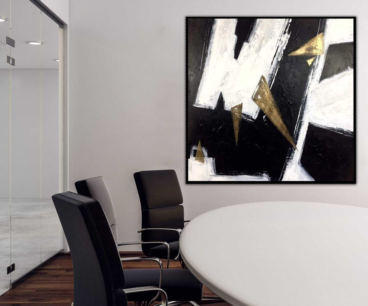 a white table with black chairs and a painting on the wall