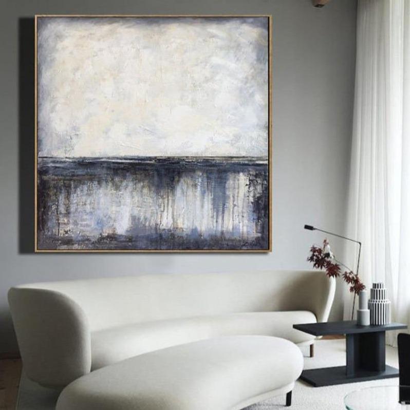 a living room with a white couch and a painting on the wall