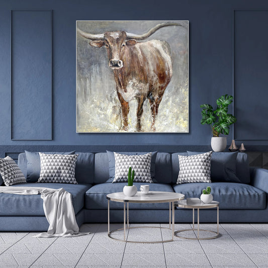 a large painting of a bull with horns hanging on a blue wall above a blue couch with patterned pillows.