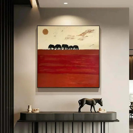 a large painting of a red landscape with a group of elephants in the background, hanging on a wall above a black console table with a small horse figurine on top.