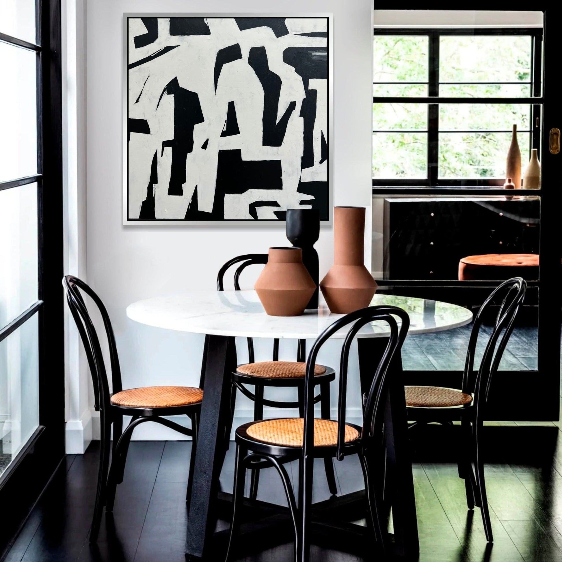a dining room table with chairs and a painting on the wall