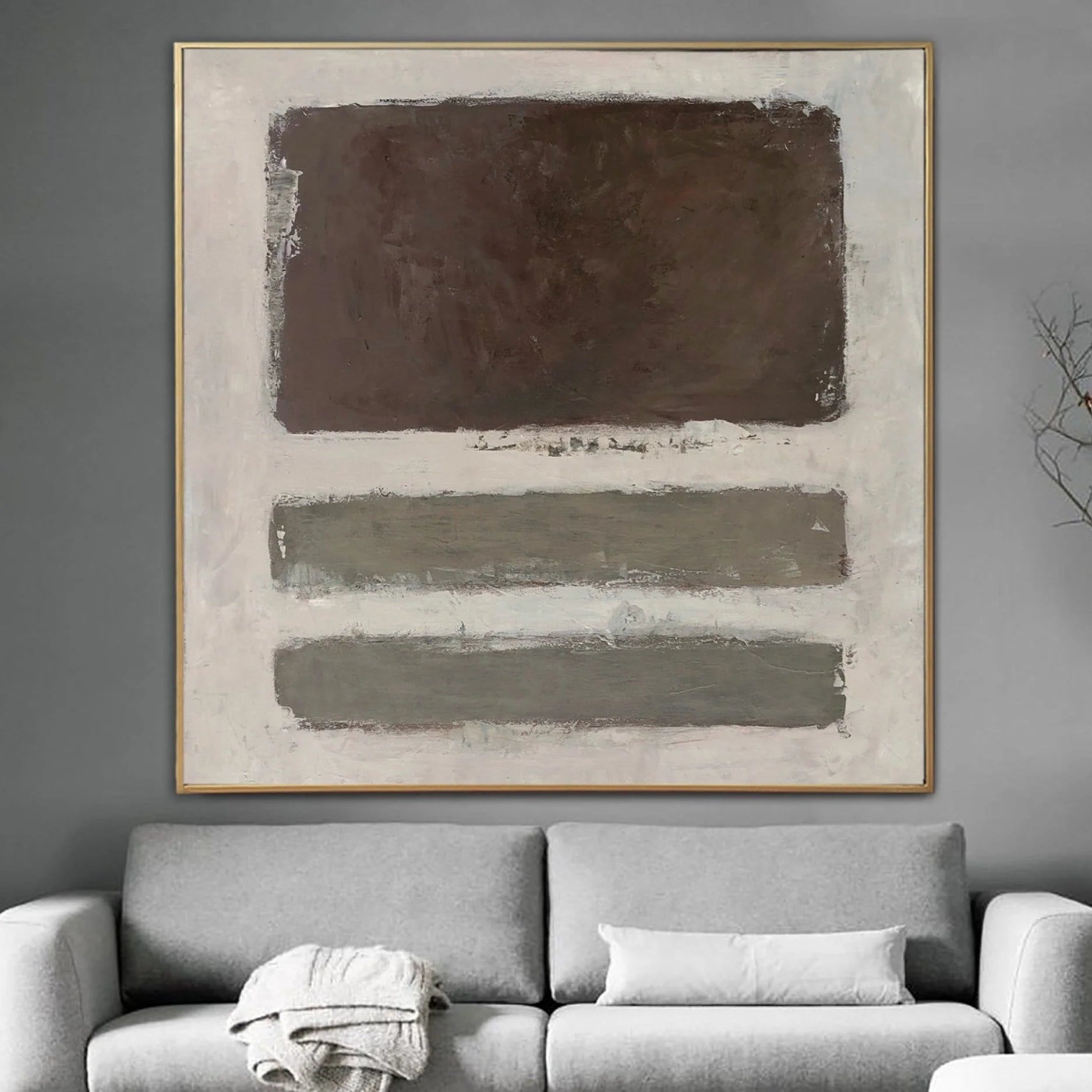 a large abstract painting hanging on a gray wall above a gray couch with white pillows.