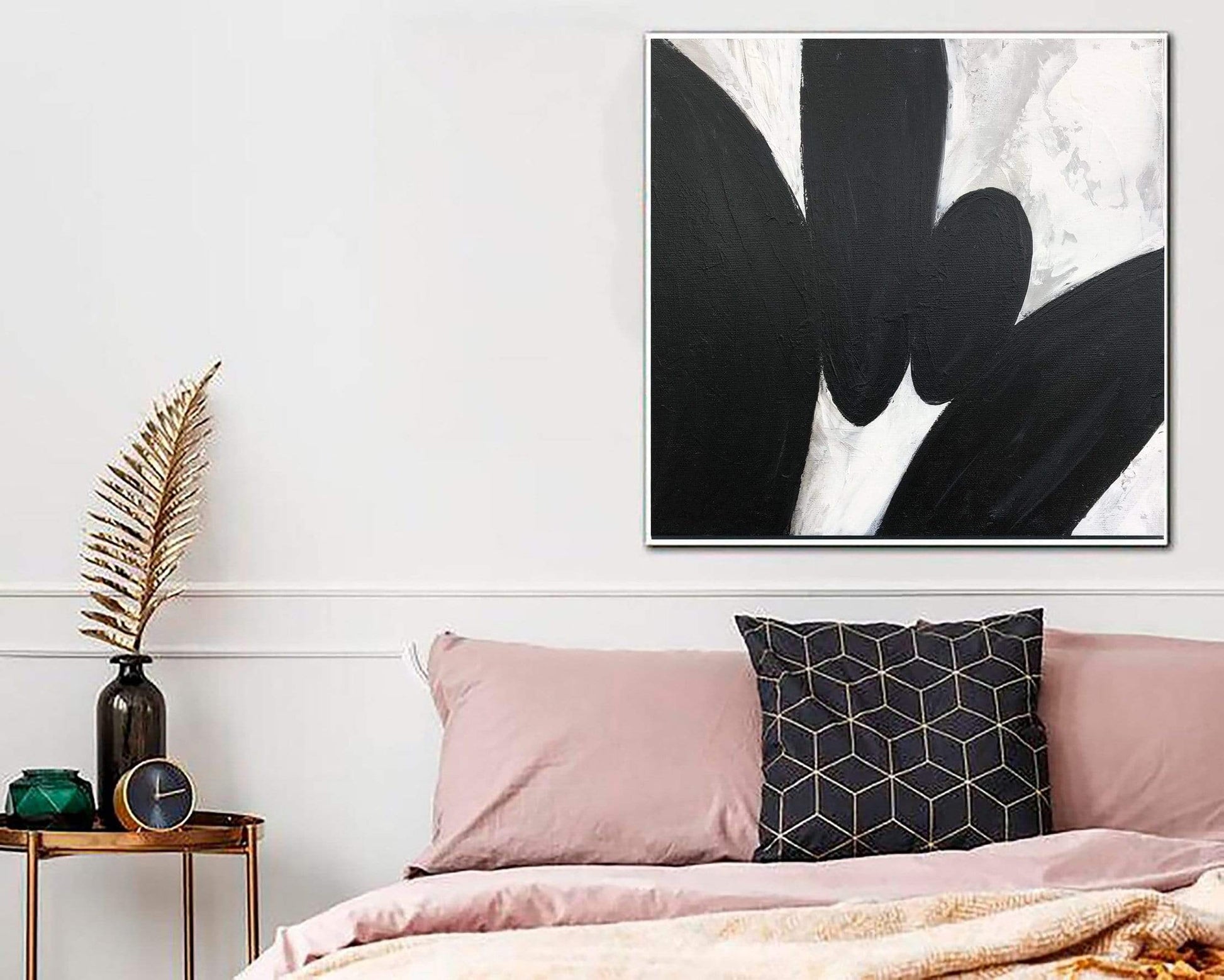 a bed with a pink comforter and a black and white painting on the wall