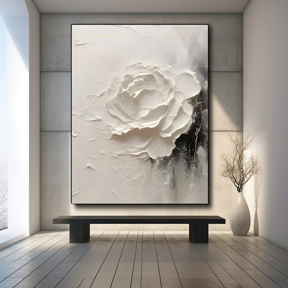 a large, square painting of a white flower hanging on a wall in a minimalist, modern room.