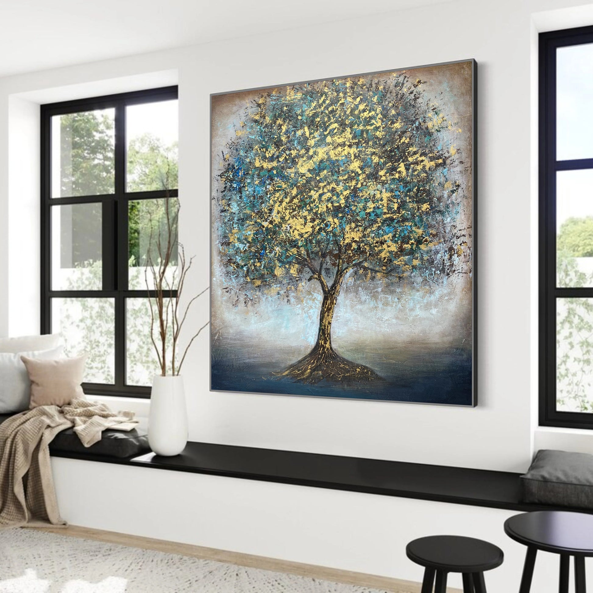 a large painting of a tree with a blue and yellow color scheme, hanging on a wall in a room with large windows.