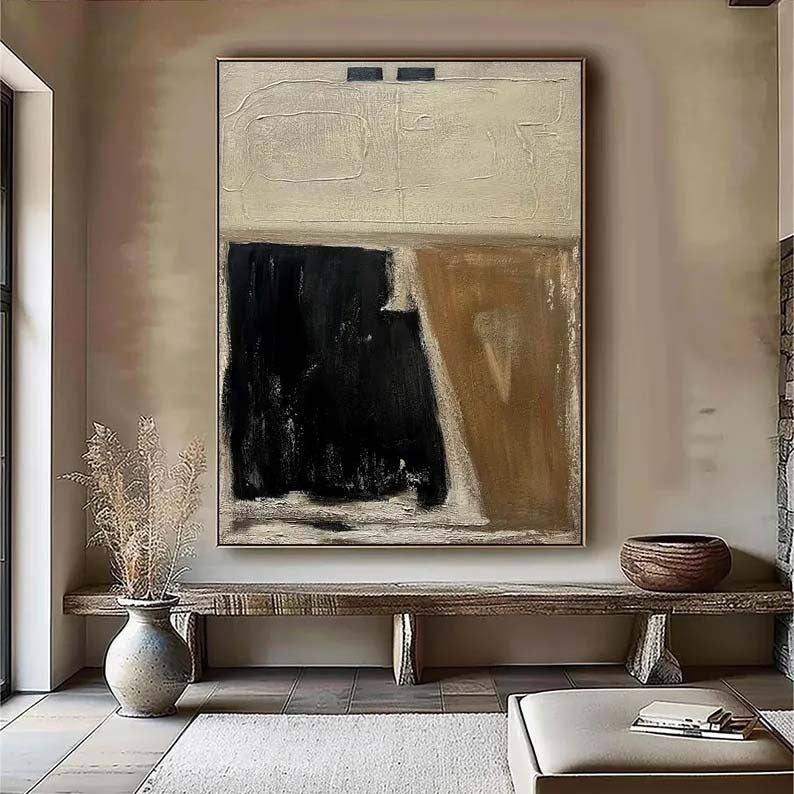 a large abstract painting hanging on a wall, with a wooden bench and a vase of dried flowers placed in front of it.