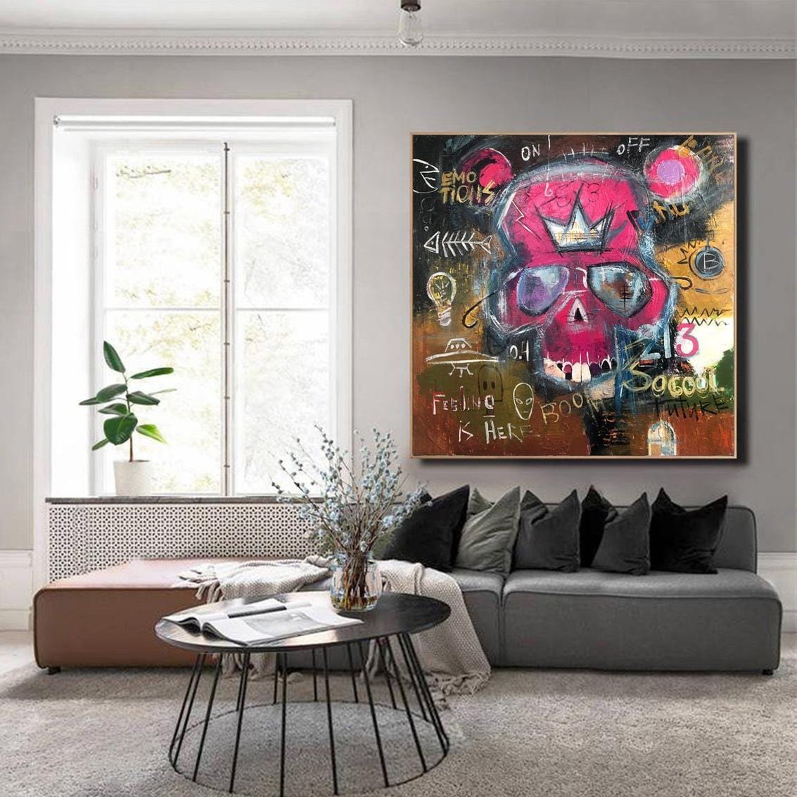 a living room with a large, colorful painting of a skull on the wall. The painting is surrounded by various other elements, such as a couch, a coffee table, and a plant. The overall scene appears to be a modern and stylish living space.