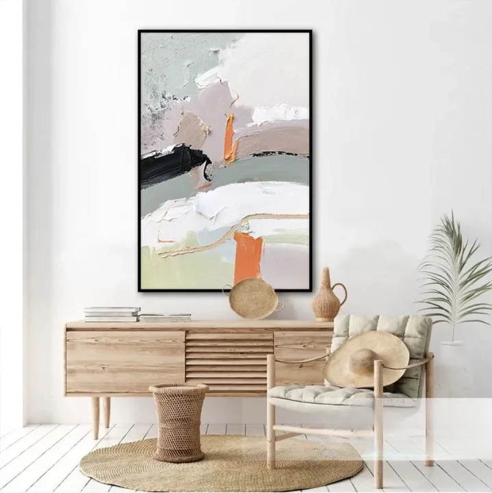 a modern and minimalist living room with a large abstract painting hanging on the wall above a wooden dresser. The dresser has a woven basket and a vase on it, adding a touch of natural elements to the space. There is also a chair and a potted plant in the room, contributing to the overall aesthetic.