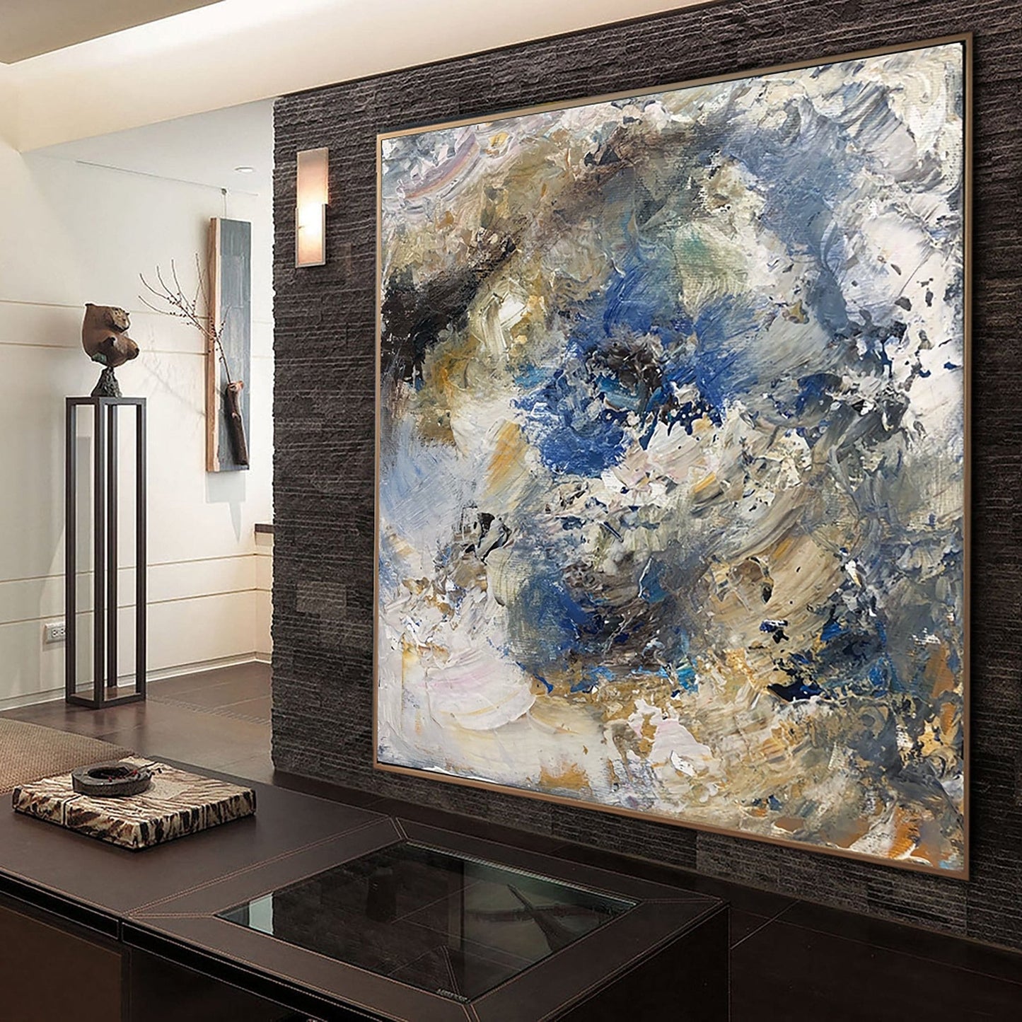 a large abstract painting displayed on a wall, with a dark wooden table in the foreground. The painting has a mix of blue, white, and brown colors, creating a dynamic and visually striking composition.