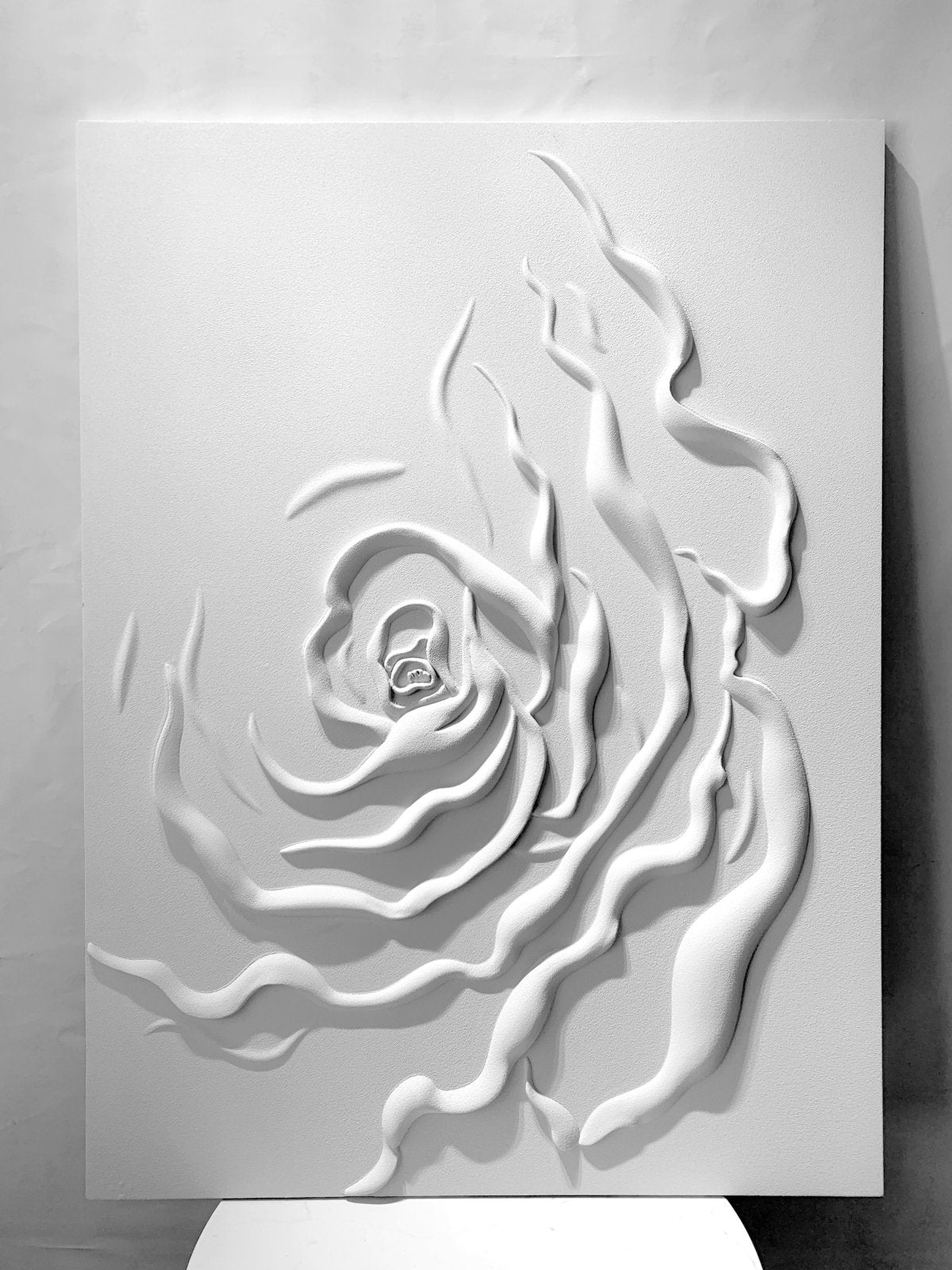 The image is a white, abstract art piece featuring a stylized, organic shape resembling a flower or plant.