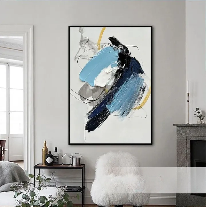 a large abstract painting hanging on a wall in a living room. The painting has a mix of blue, black, and white colors, creating a dynamic and visually striking composition.
