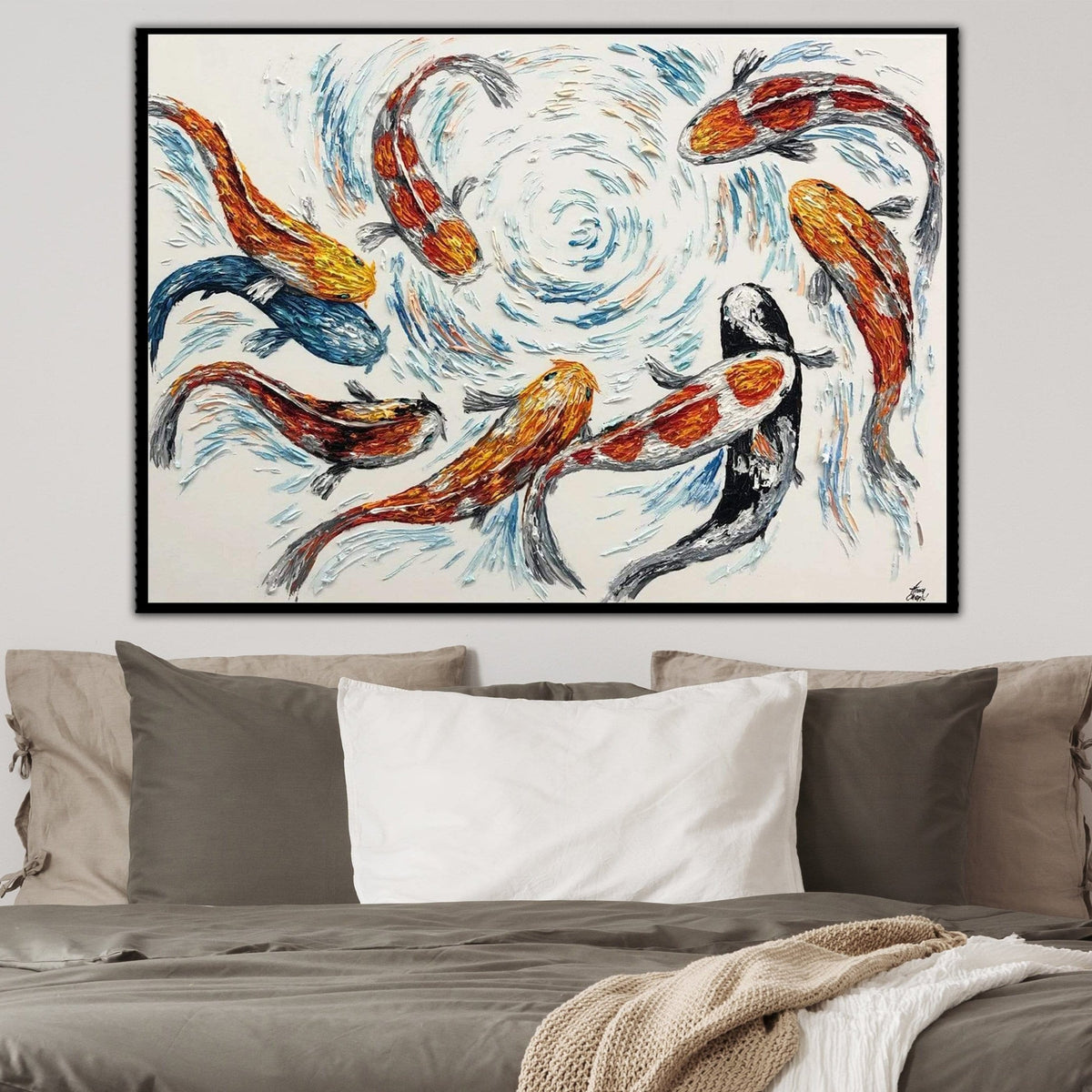 a large painting of colorful fish swimming in a swirling pattern, hanging on a wall above a bed with pillows.