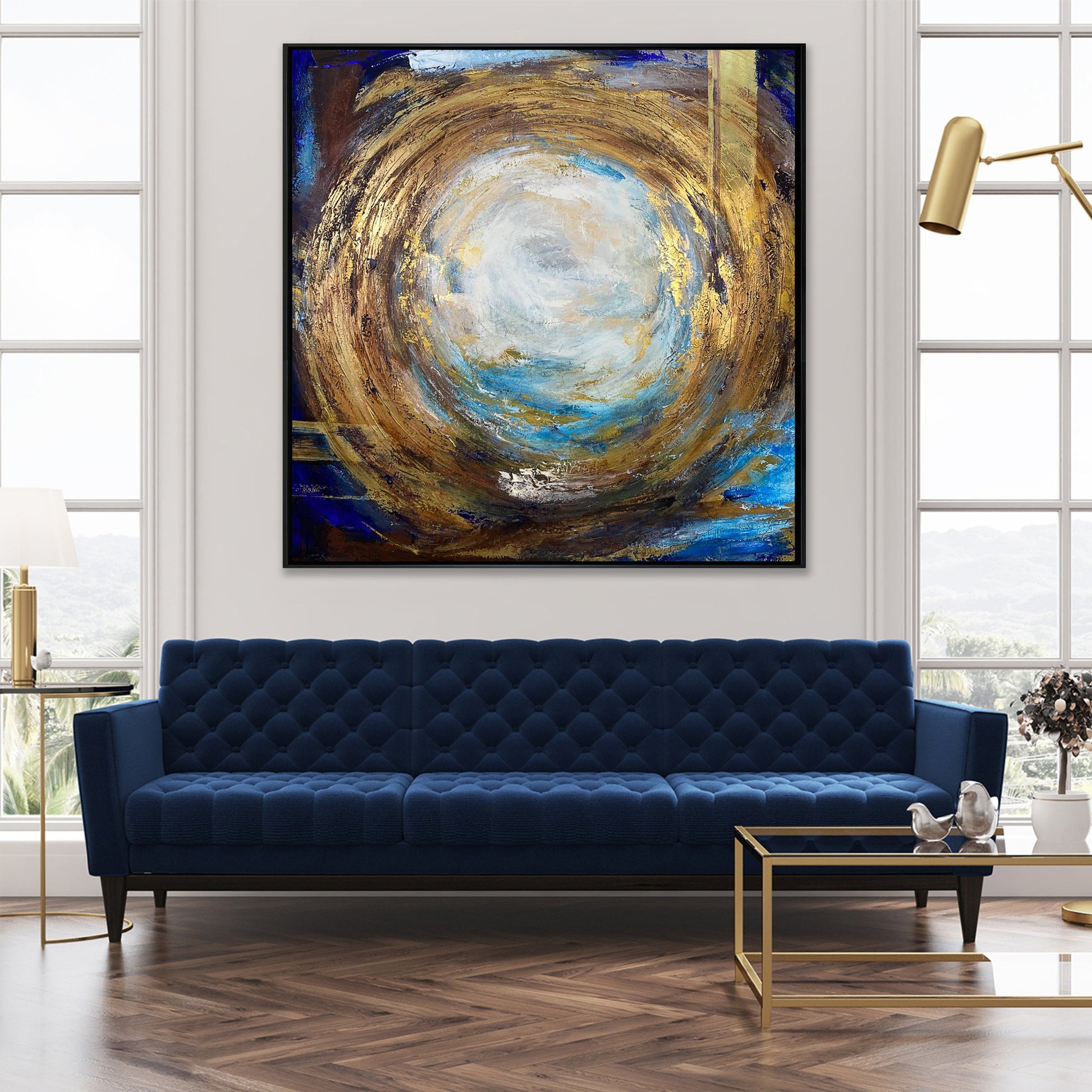 a large abstract painting hanging on a wall above a blue tufted sofa in a modern living room.