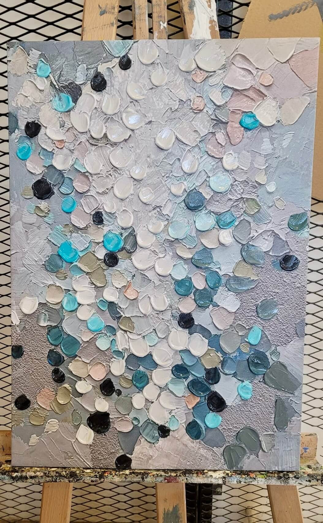 The image is an abstract painting featuring a variety of colors and textures, including shades of blue, gray, and white, as well as some darker tones. The painting appears to be a collage of multiple smaller images, creating a visually striking and dynamic composition.