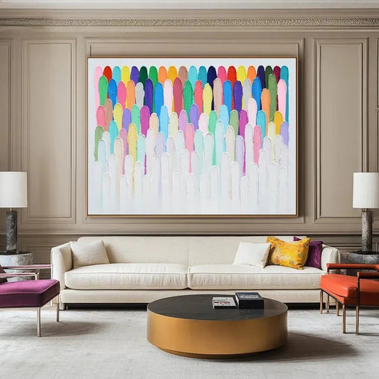 a modern living room with a large abstract painting hanging on the wall above a white sofa. The sofa is positioned in front of a round coffee table, which has a black top. The room also includes two lamps and a few books, creating a cozy and stylish atmosphere.